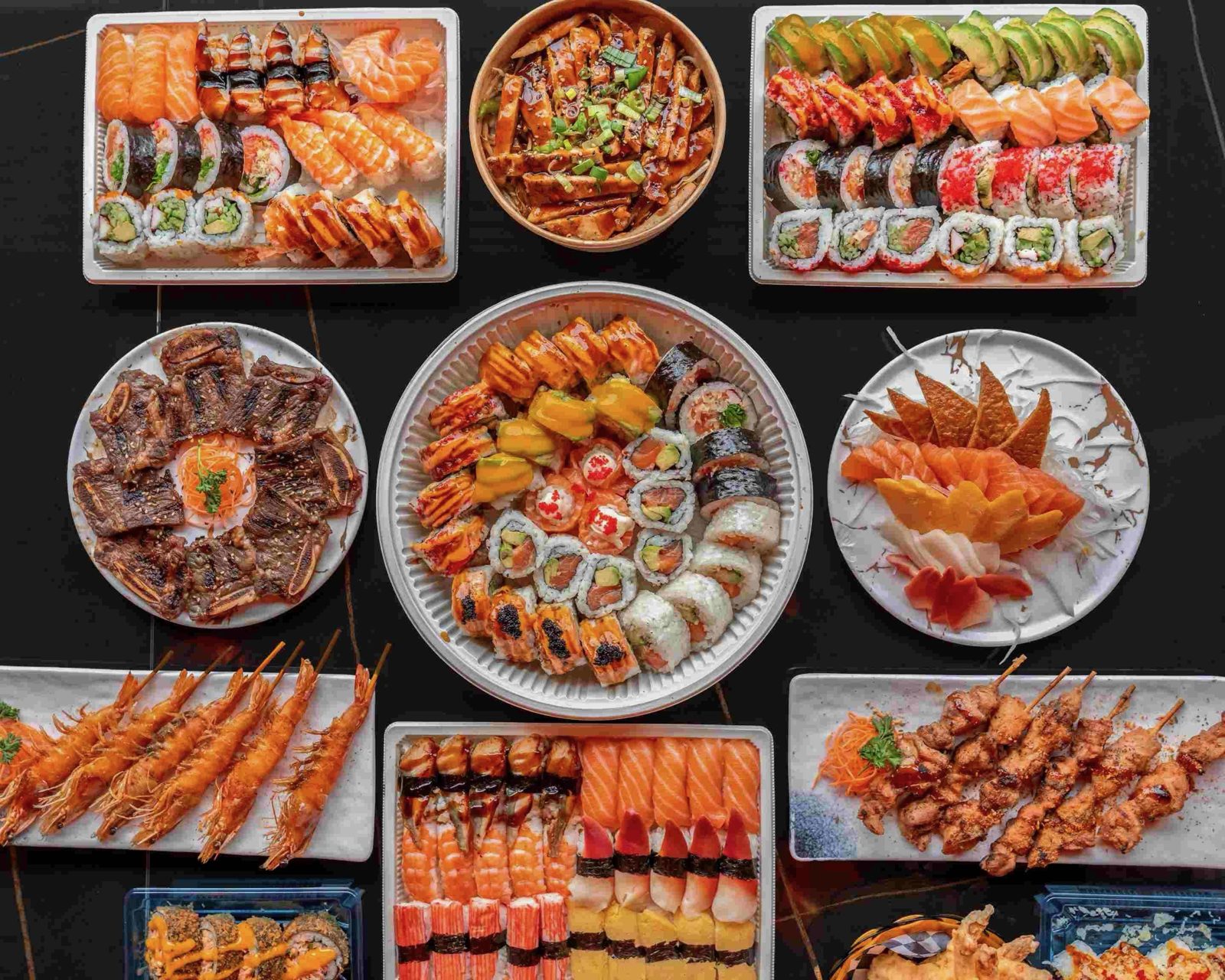 Vue du dessus d'une table garnie : sushi brûlés, makis, sashimi, crevettes et brochettes